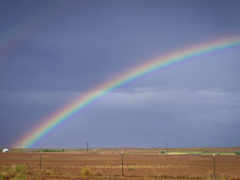 Scenic view of rainbow over field against sky