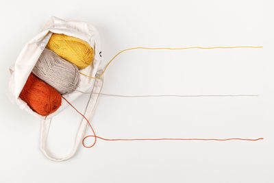 Yellow, red and beige clews of yarn in a bag. strings of yarn form a line for the text. copy space.