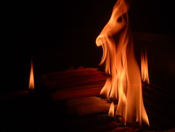 Close-up of burning candle against black background