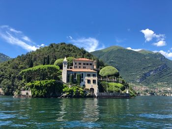 Building by lake and mountains against sky