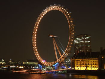 Illuminated ferris wheel in city at night