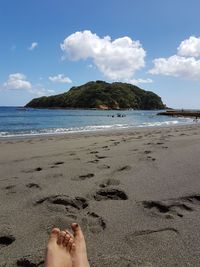 Low section of woman on beach against sky