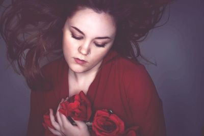 Close-up of young woman with red rose