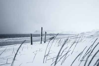 Scenic view of snow covered land by sea against sky