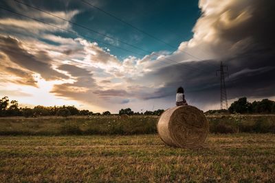 Hay bales on field against sky during sunset