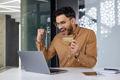 Young woman using phone while sitting at office