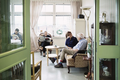 Caretakers with senior couple sitting in living room at nursing home