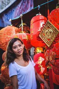 Portrait of smiling young woman standing by lantern