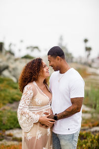 Mixed race couple posing for maternity photos on beach