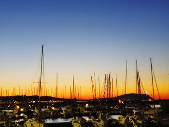 Sailboats moored at harbor during sunset