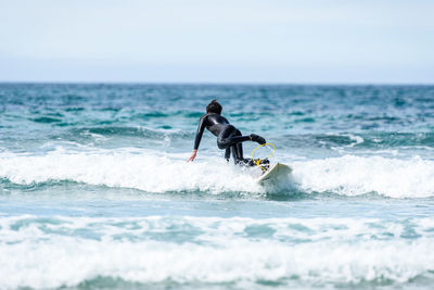 Man surfing in sea against sky