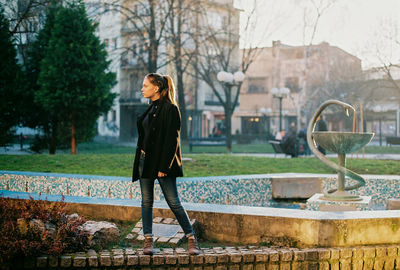 Woman standing by plants against trees