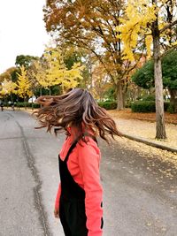 Woman standing on road by tree in city