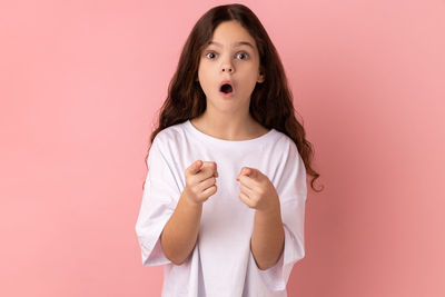 Portrait of young woman against pink background