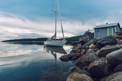 Sailboats moored on sea against sky