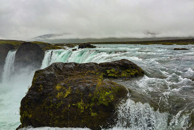 Scenic view of waterfall against sky