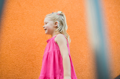 Portrait of young woman standing against wall