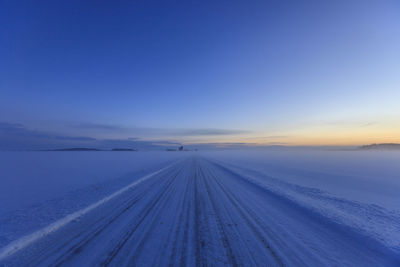 Scenic view of snow covered landscape against blue sky during sunset