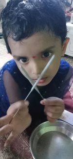 Close-up portrait of cute boy holding camera