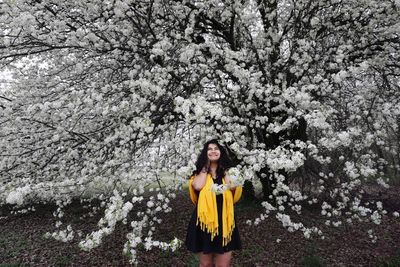 Portrait of young woman standing against yellow tree