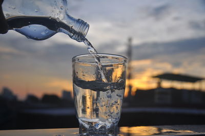 Close-up of drink in glass against sky during sunset