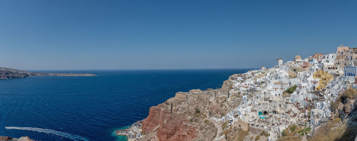 Aerial view of city by sea against blue sky