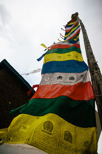 Low angle view of multi colored flags on building against sky