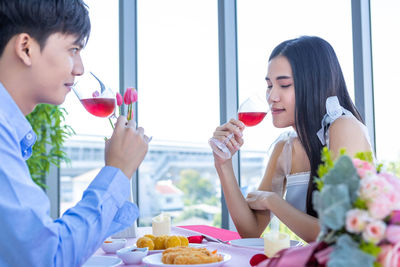 Beautiful young woman sitting on table with people in background