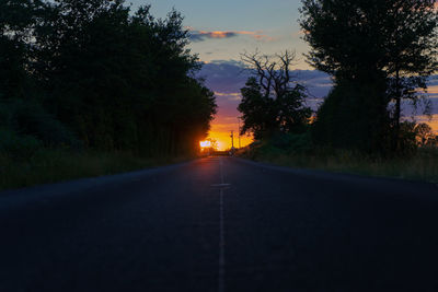 Road amidst trees against sky during sunset