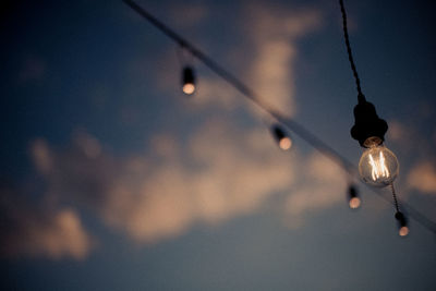 Low angle view of illuminated light bulb against sky at night