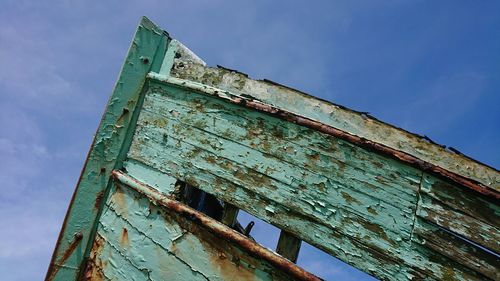 Low angle view of old rusty metallic structure against blue sky