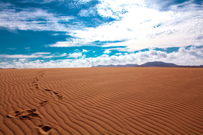 Scenic view of sand dunes against dramatic sky