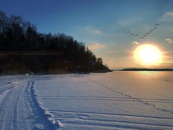 Scenic view of snow covered landscape against sky during sunset