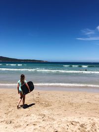 Full length of woman on beach against blue sky