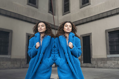 Portrait of a young woman standing against building in city