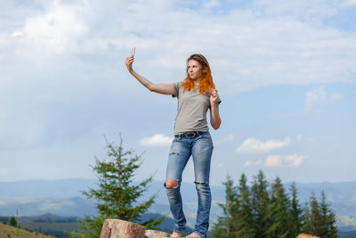 Girl makes selfie on a smartphone against the background of the carpathian mountains