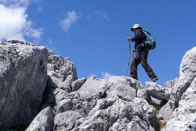 Low angle view of man standing on rock against sky