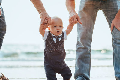 Cute boy with parents walking on beach