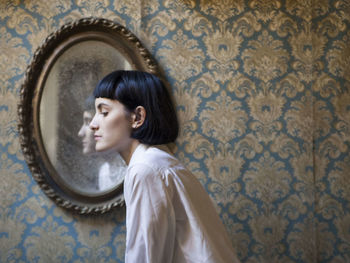 Side view of woman against mirror at home