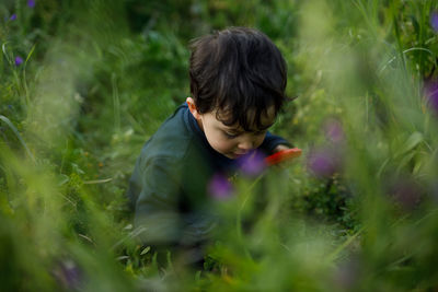 Side view of boy looking away while standing on field