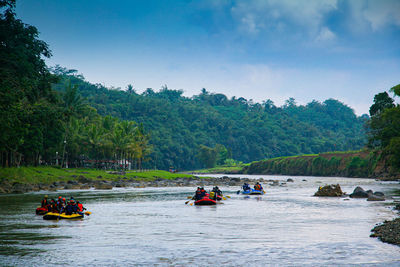 People on boat in river against sky