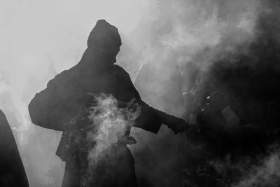 Smoke surrounded by man carrying incense burner