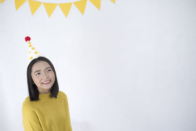 Portrait of a smiling young woman standing against wall