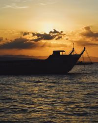 Silhouette sailboat sailing on sea against sky during sunset