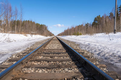 Surface level of railroad tracks against sky during winter