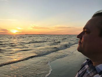 Close-up of man on beach against sky during sunset