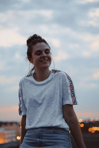 Portrait of smiling young woman standing against sky