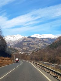 Road amidst snowcapped mountains against sky