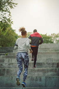 Rear view of man and woman moving up staircase