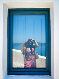 Rear view of young woman photographing through window